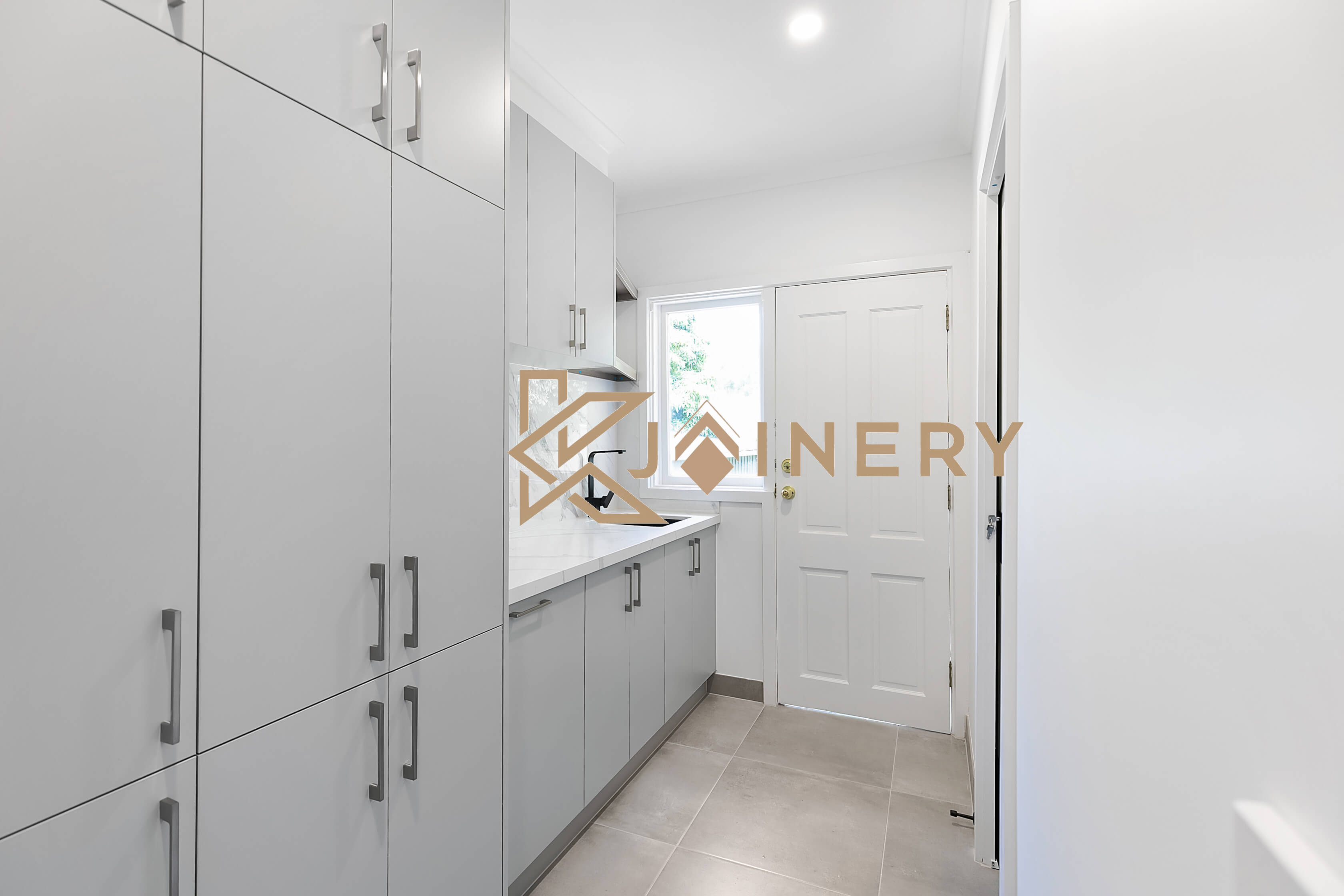 The same Melbourne laundry after custom joinery with full height cabinetry and a bench over the machines