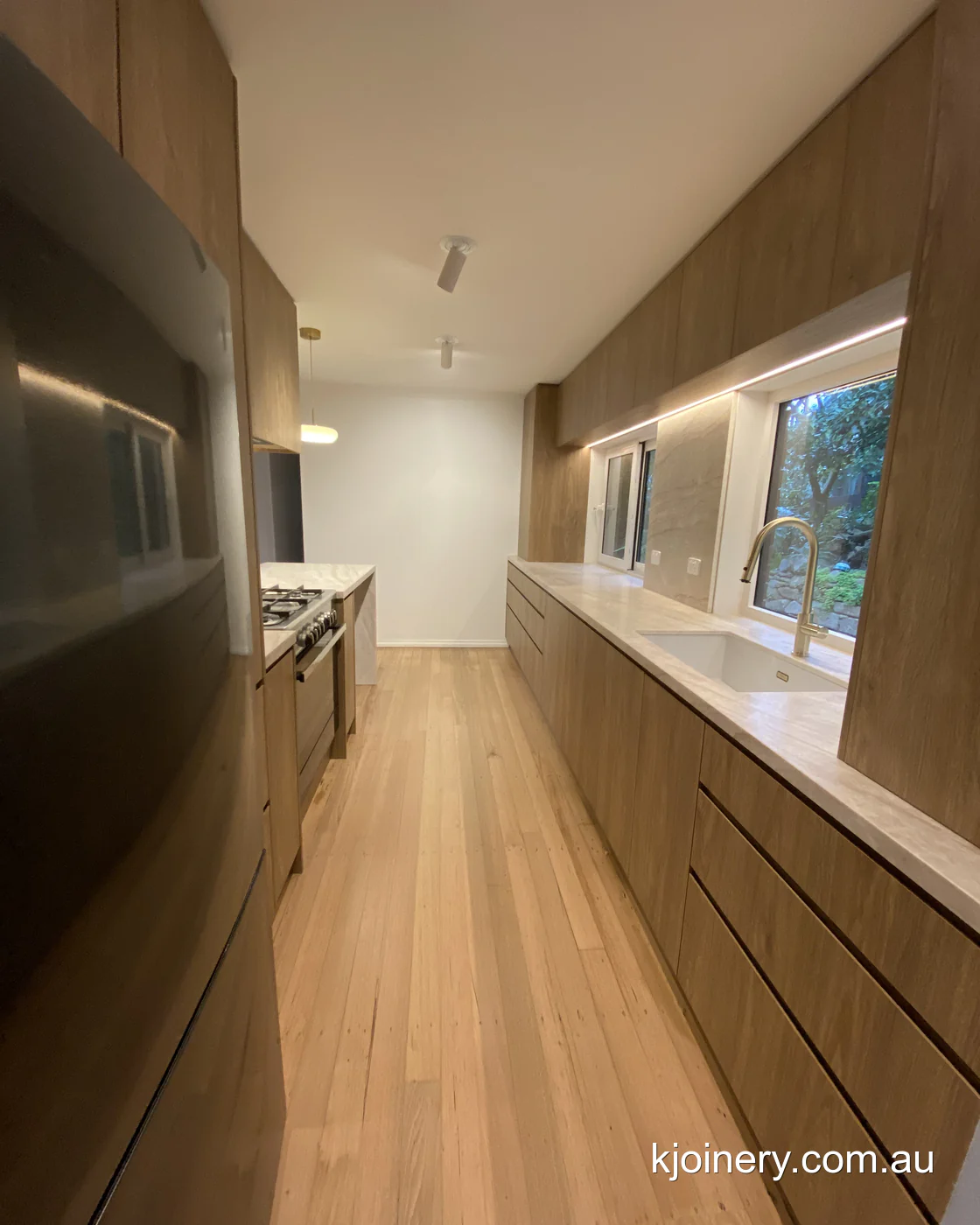 Raked ceiling kitchen in Essendon with tall oak cabinetry cut to the roof pitch