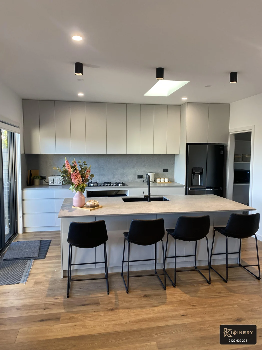 Kitchen joinery Altona island showing breakfast bar seating with black bar stools, undermount black sink and rear cabinetry