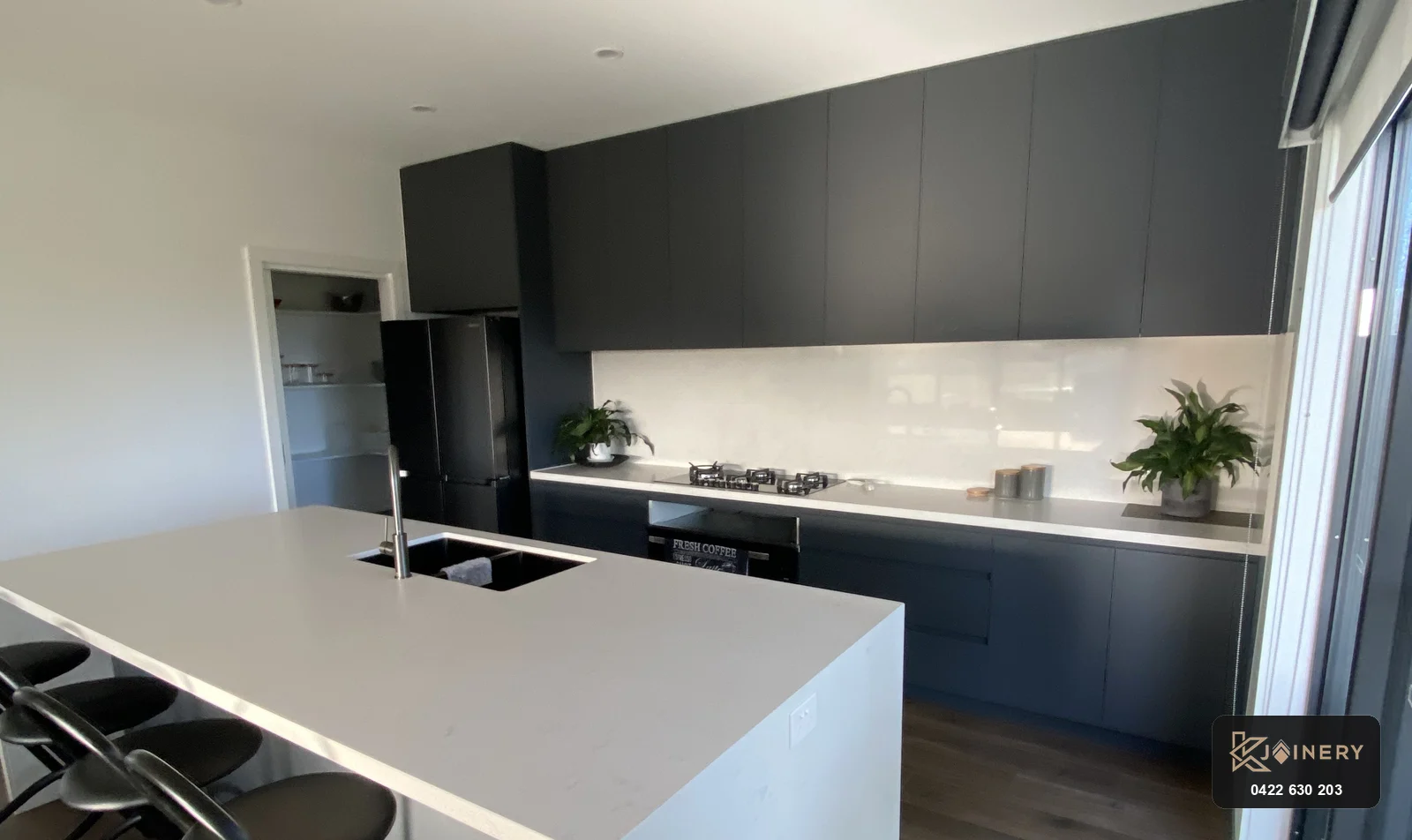 Modern kitchen renovation in Altona featuring Laminex AbsoluteMatte dark cabinetry and stone waterfall island