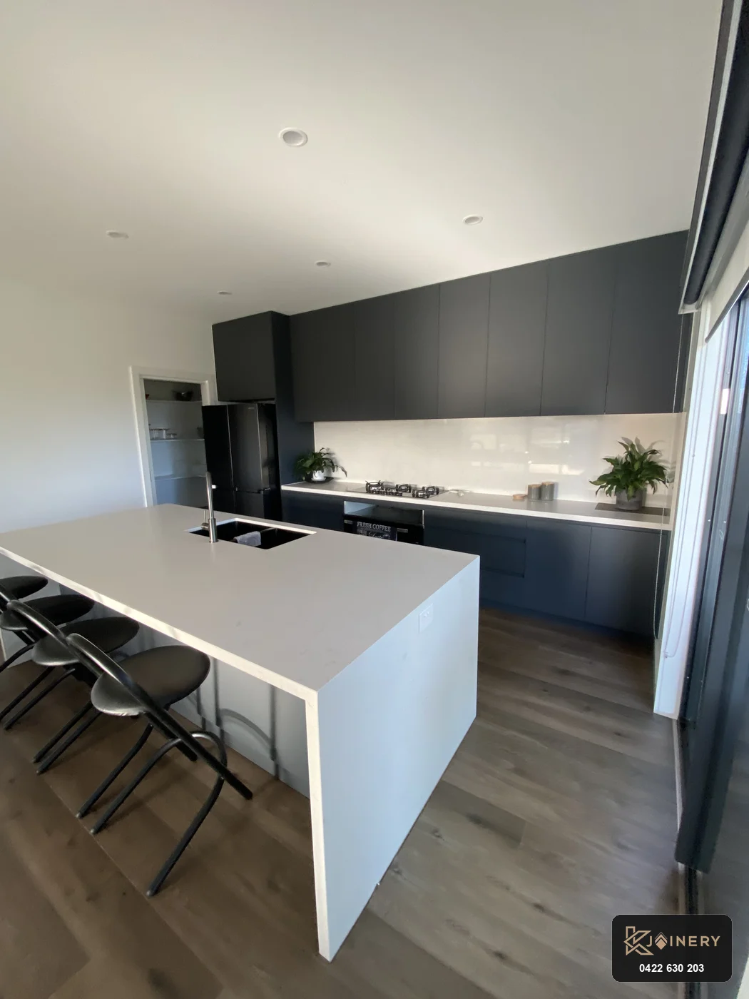 Elevated angle of Altona kitchen showing continuous overhead bulkhead and integrated gas cooktop run
